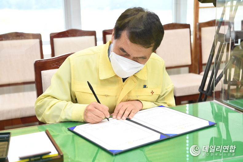 박성일 완주군수가 "도농상생 공공급식 교차공급" 업무 협약에 사인을 하고 있다(사진=완주군청)
