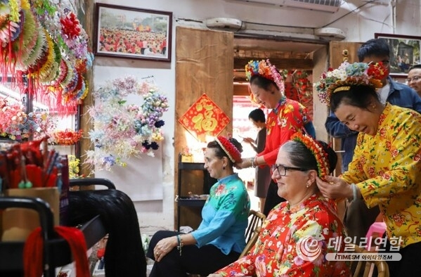 Photo shows that foreign tourists are experiencing Xunpu flowery headwear, a national intangible heritage in Xunpu Village.