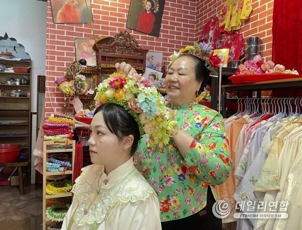 Photo shows a villager pins a flowery headwear for a tourist at Xunpu Village of Quanzhou City, southeast China's Fujian Province. Photo shows a villager pins a flowery headwear for a tourist at Xunpu Village of Quanzhou City, southeast China's Fujian Province.
