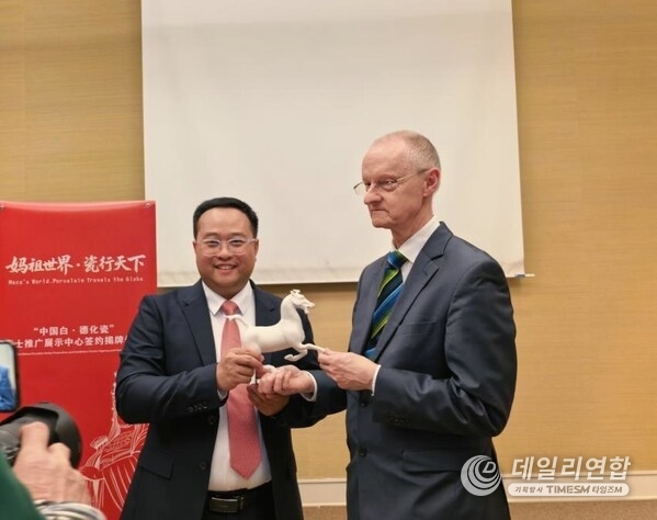 Photo shows Fang Junqin, Party Chief of Dehua County in southeast China's Fujian Province, presenting Dehua white porcelain to international guests in Geneva, Switzerland, on Feb. 24, 2026.